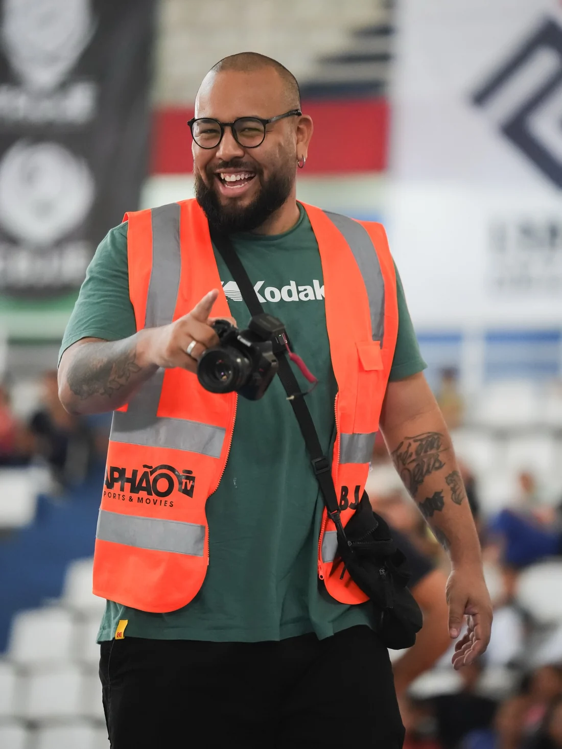 Raphão de colete laranja e câmera na mão, num campeonato